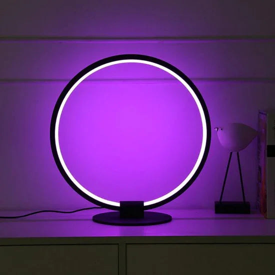 Moderne runde LED-Tischlampe mit lila Licht auf Sideboard, stilvolles Wohnaccessoire