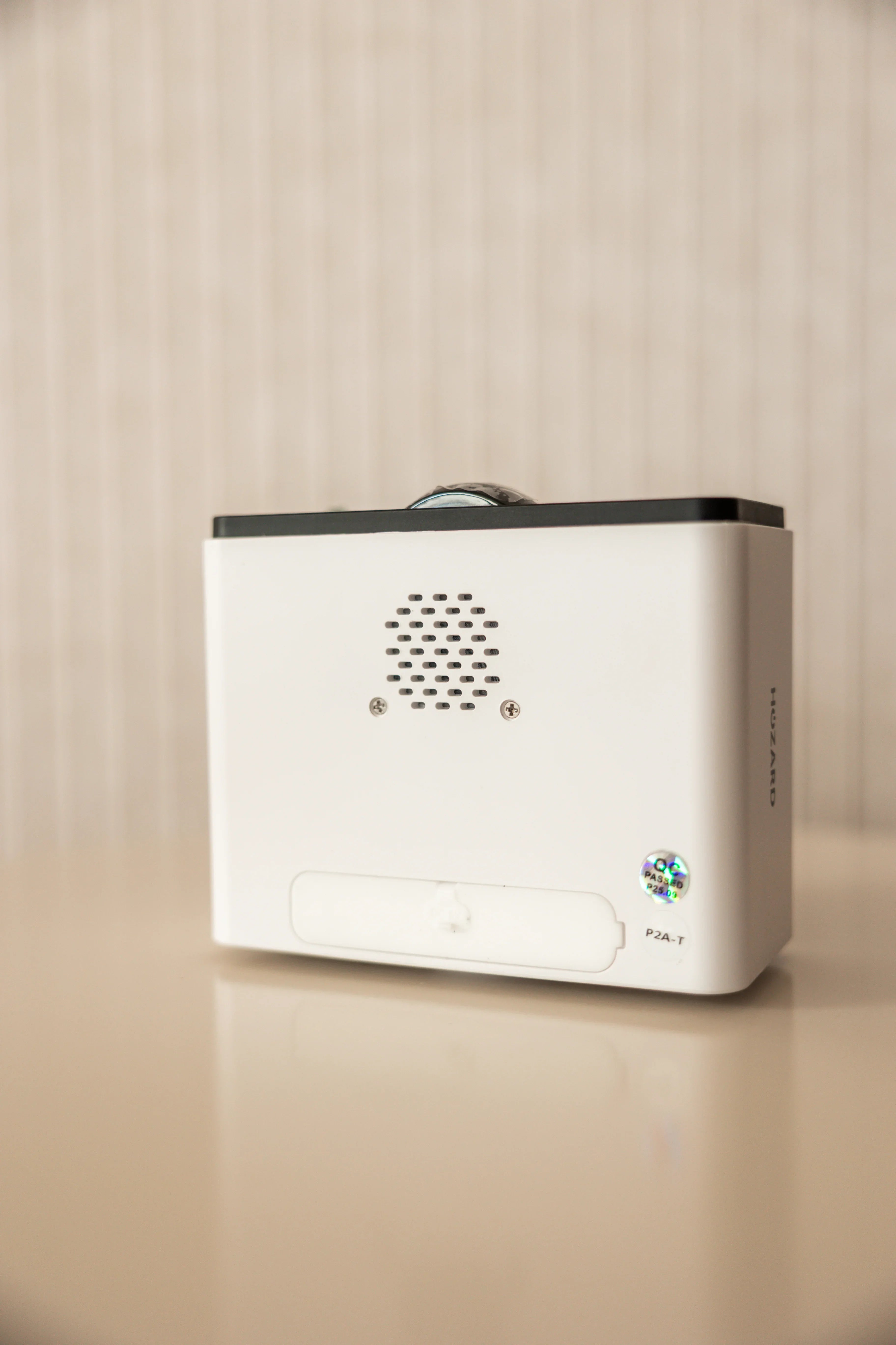 Moderne, weiße Alarmanlage mit Lautsprechergitter auf Tisch, Wohnumgebung, Hozard sichtbar